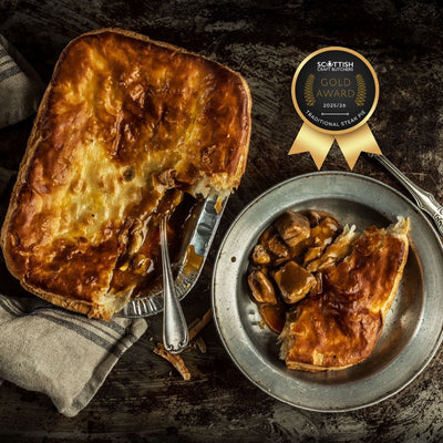 A steak pie with a slice cut out, served on a metal plate with diced steak from the stew spilling out, on a rustic background. An inset of a medal for winning the Gold Award 2025/26 in the Traditional Steak Pie category.